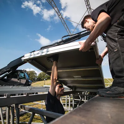 stagehand som lyfter podie på site i skåne